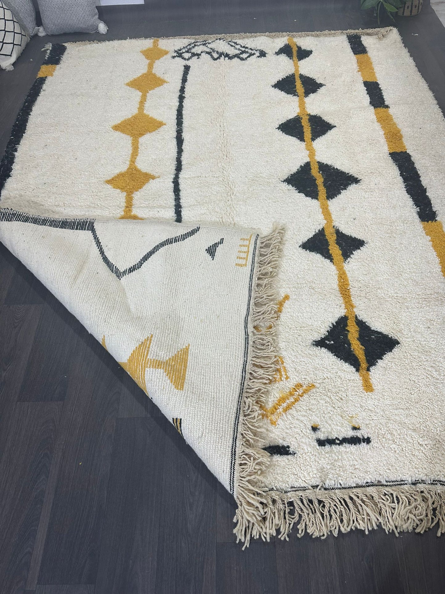 Amal is an off white Moroccan wool rug with black and mustard coloured lines and diamonds in the tribal design.