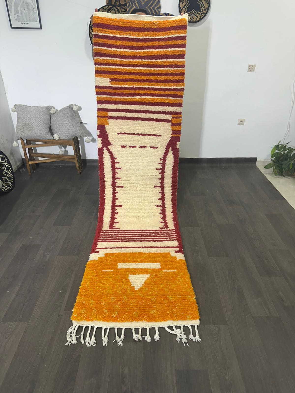 Long, colorful rug with striped pattern on a wooden floor.