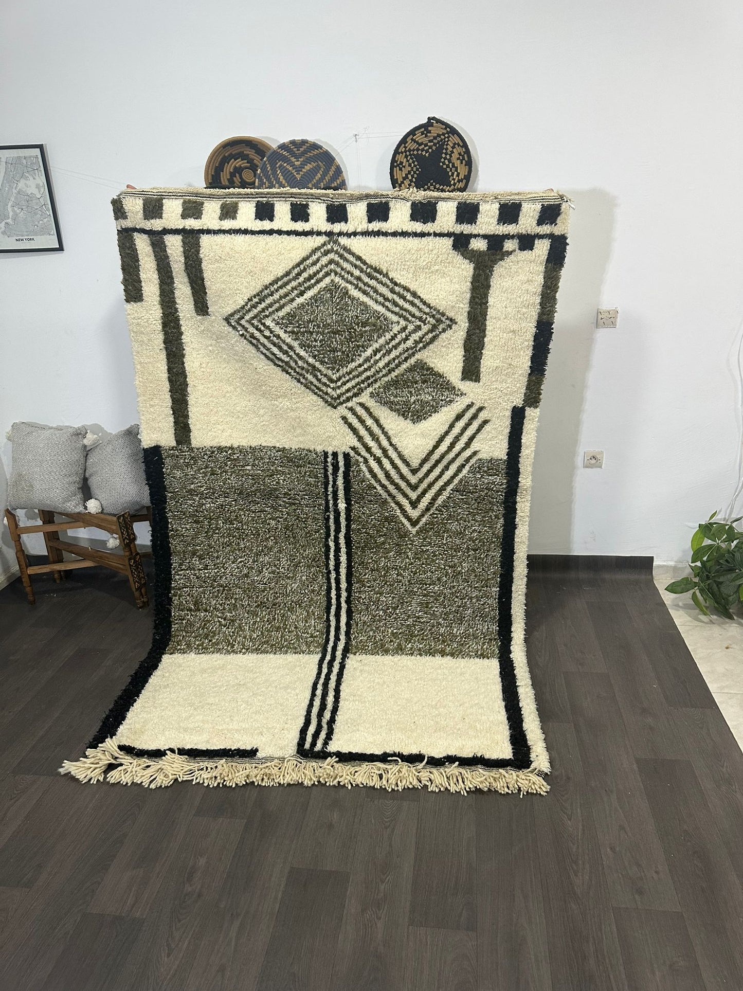 Geometric patterned Moroccan wool rug on a wooden floor with a white wall background