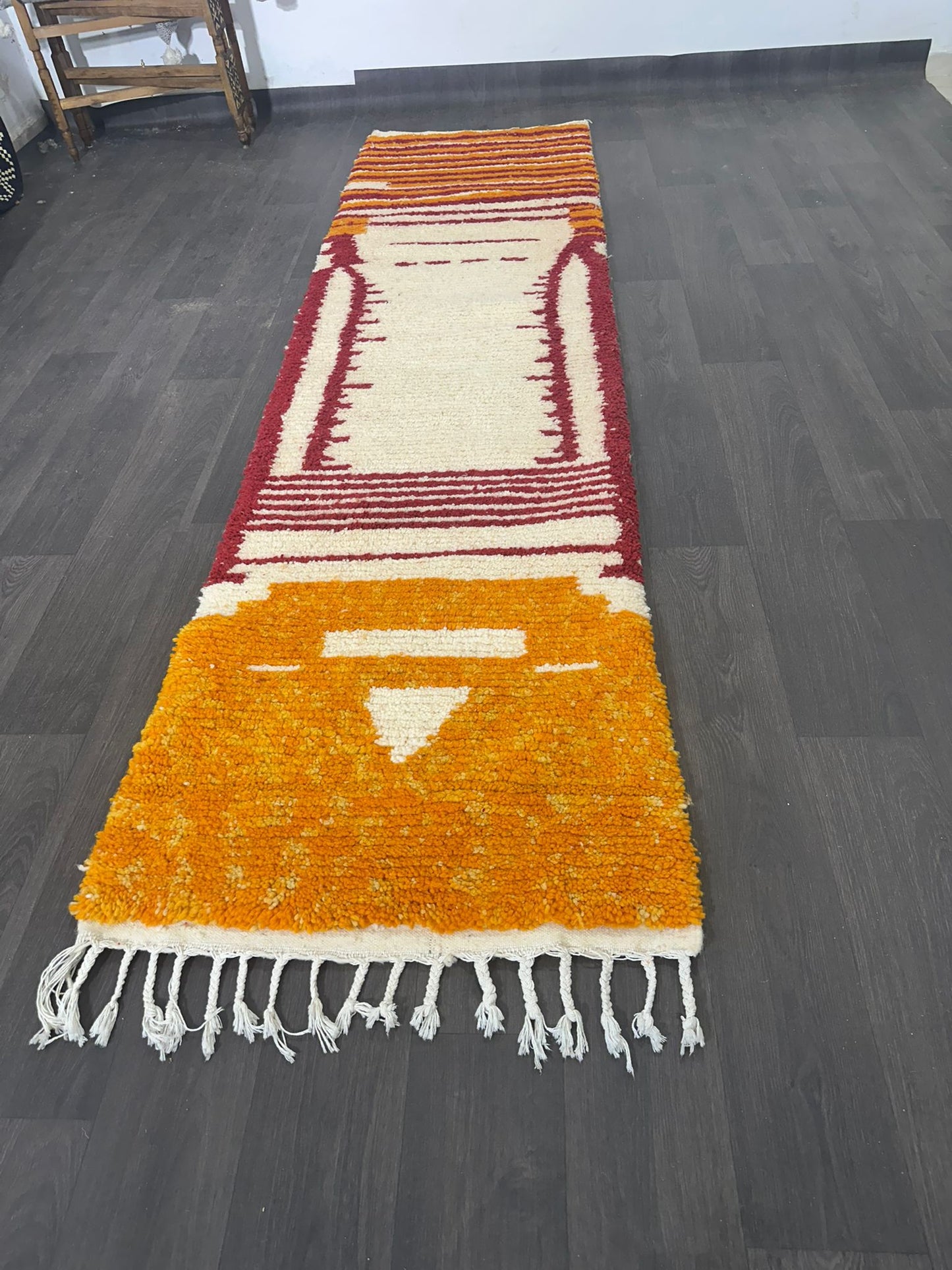 Colorful new Moroccan wool runner rug with geometric pattern on a dark wooden floor