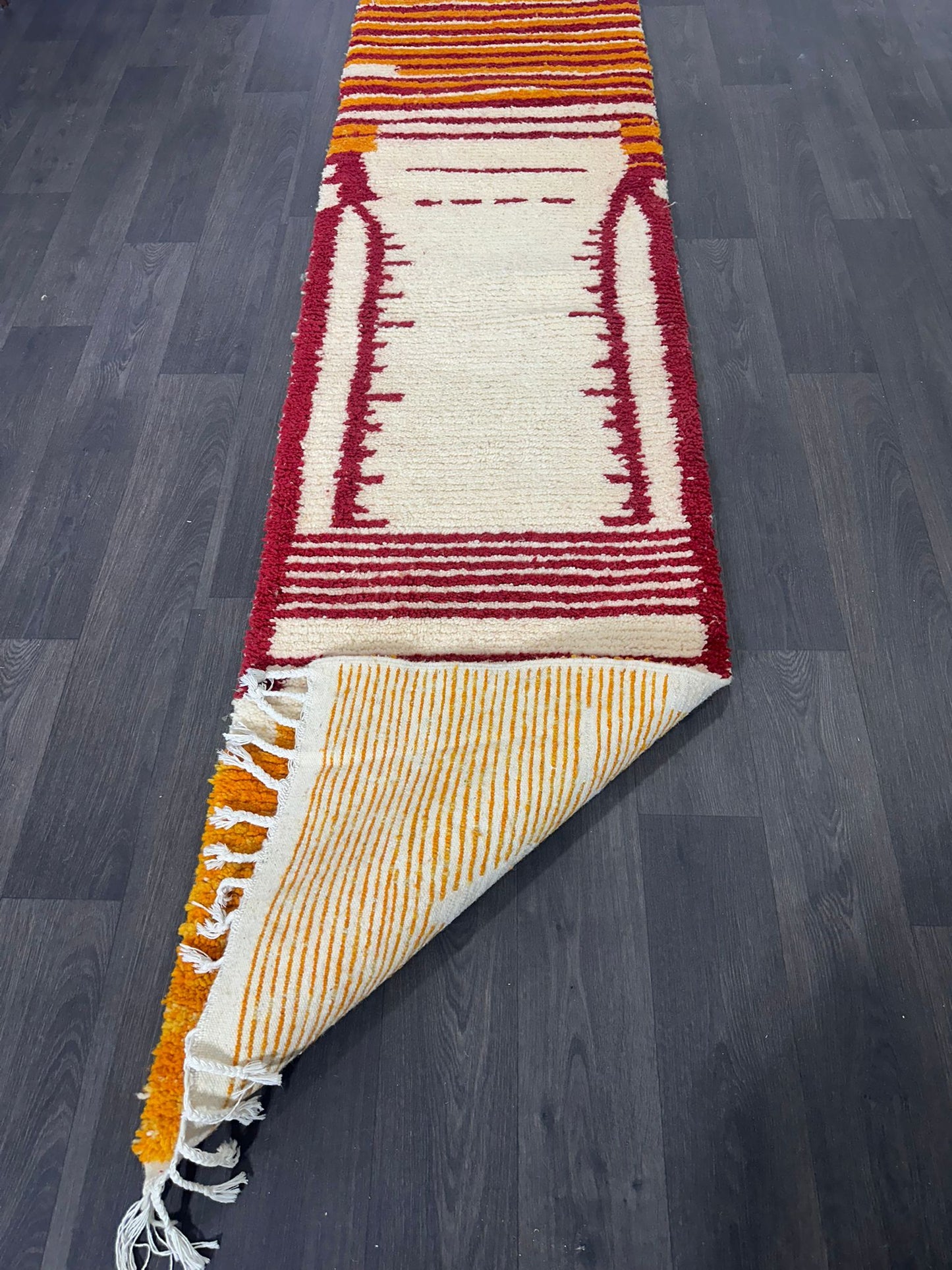 Colorful new Moroccan wool runner rug with geometric pattern on a dark wooden floor