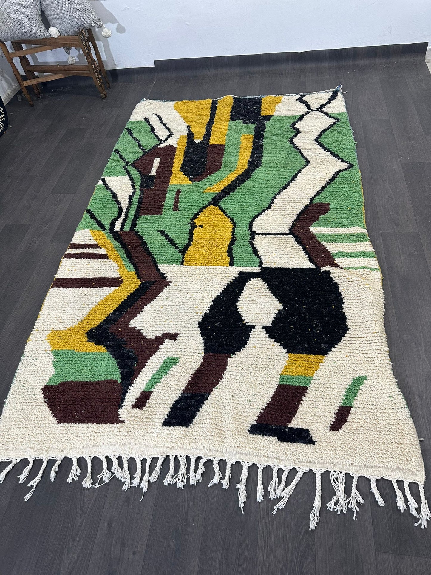 Geometric patterned Moroccan wool rug with colorful design on a wooden floor.