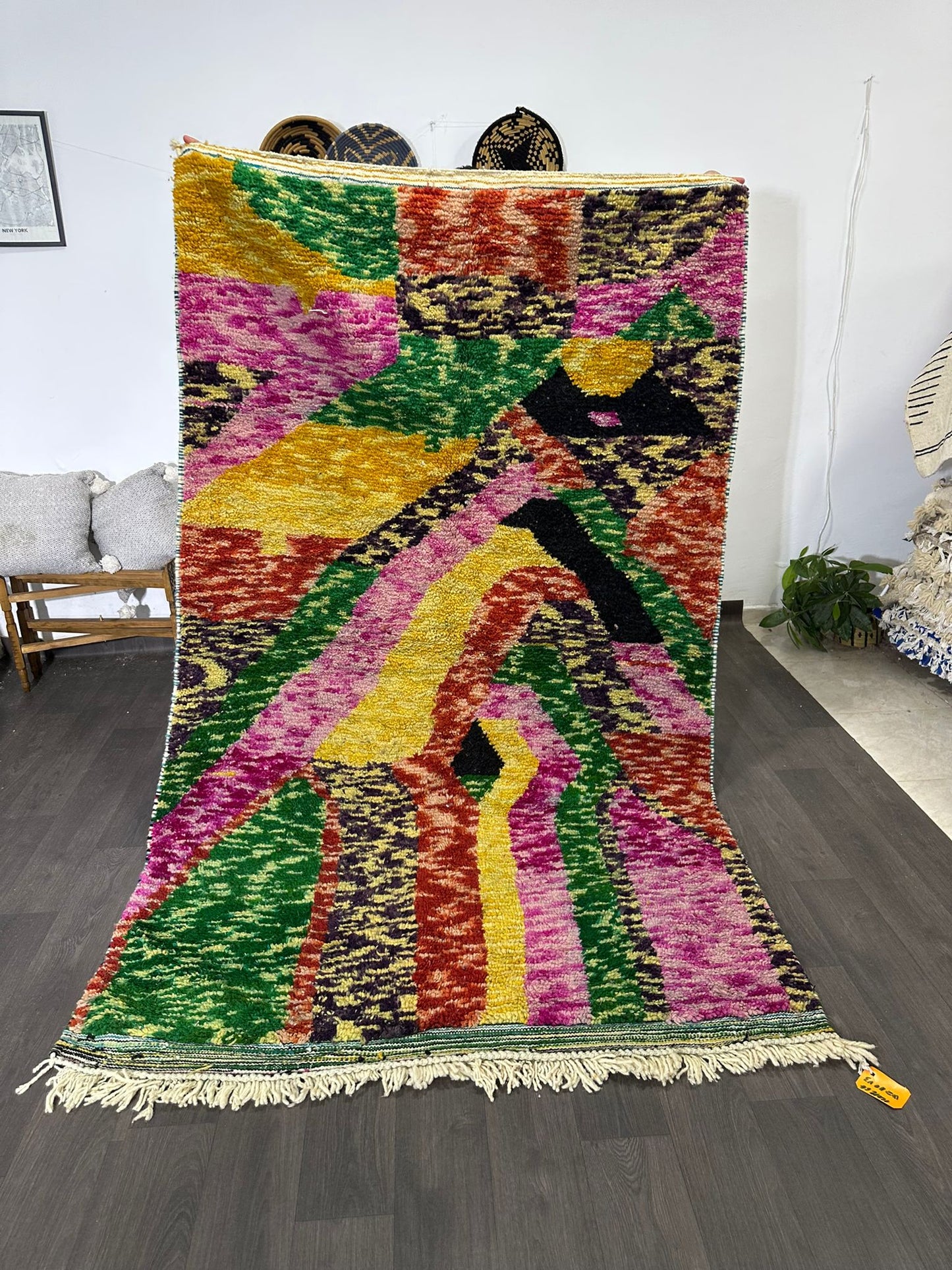 Colorful geometric-patterned rug on a wooden floor with a white wall background