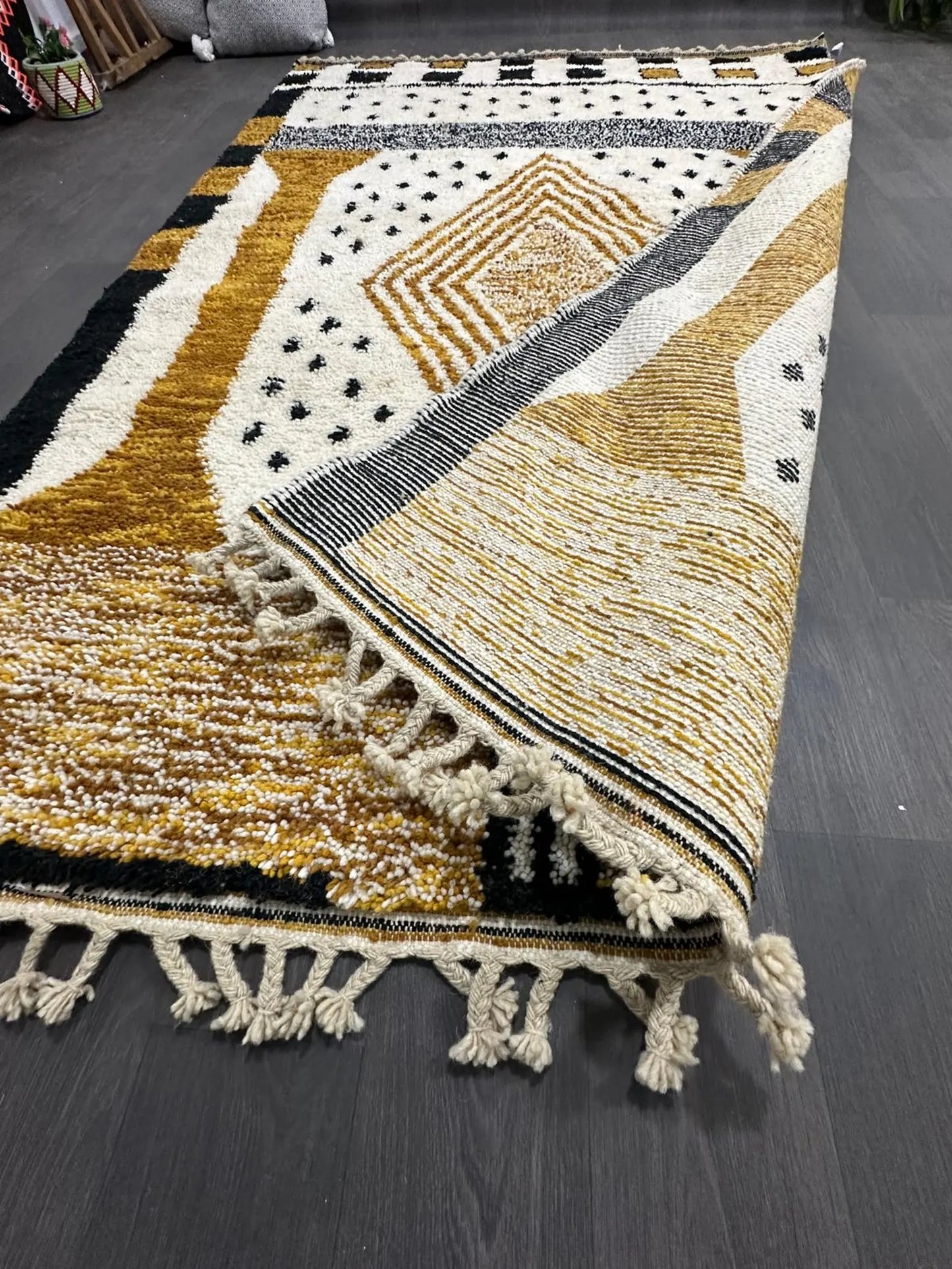 Decorative rug with geometric pattern and tassels on a dark wooden floor