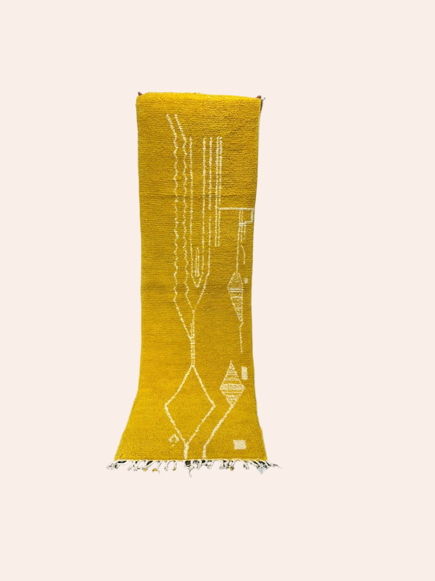 Yellow patterned rug on a wooden floor with a white wall background