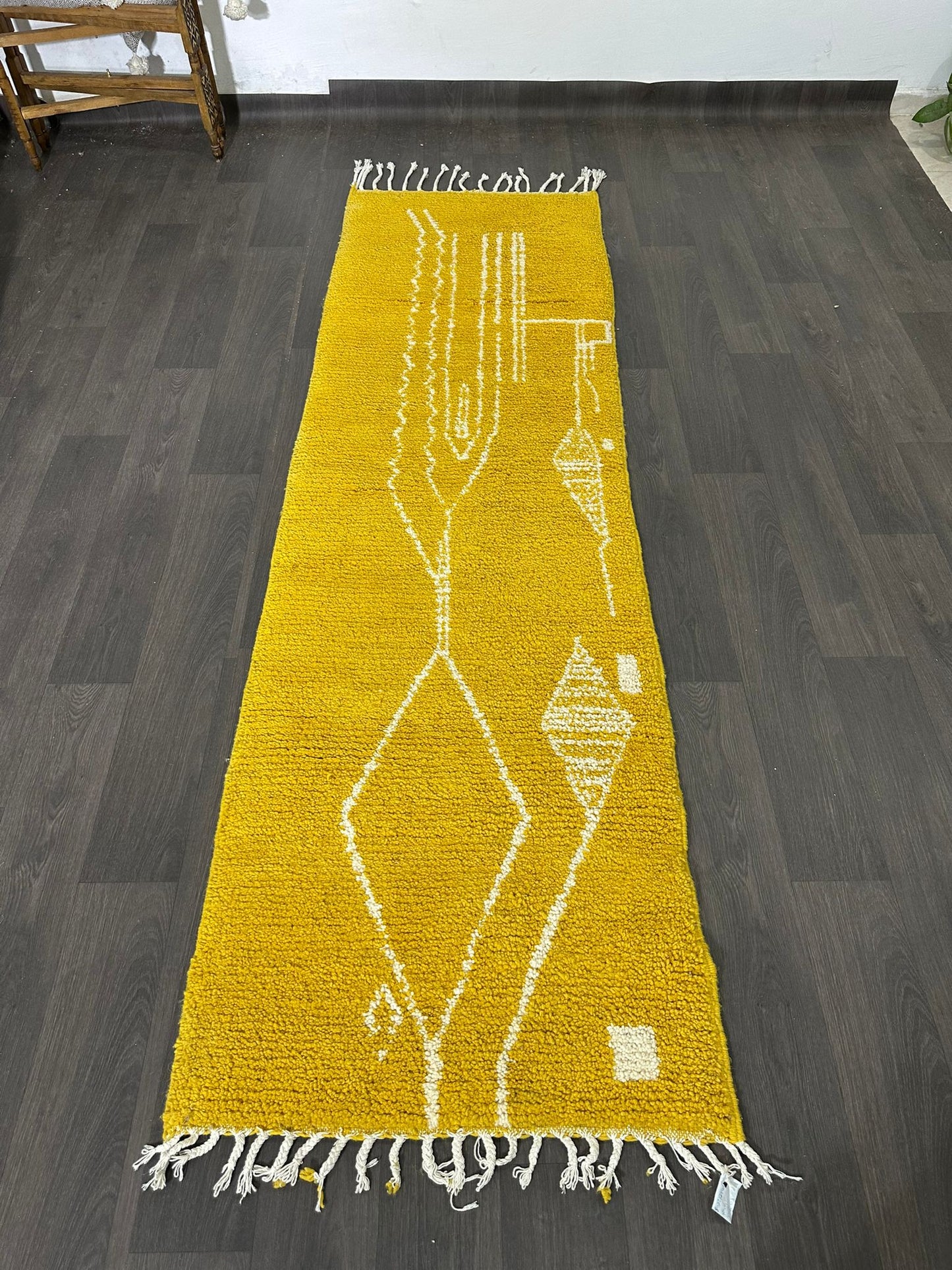 Yellow runner rug with white geometric patterns on a dark wooden floor.
