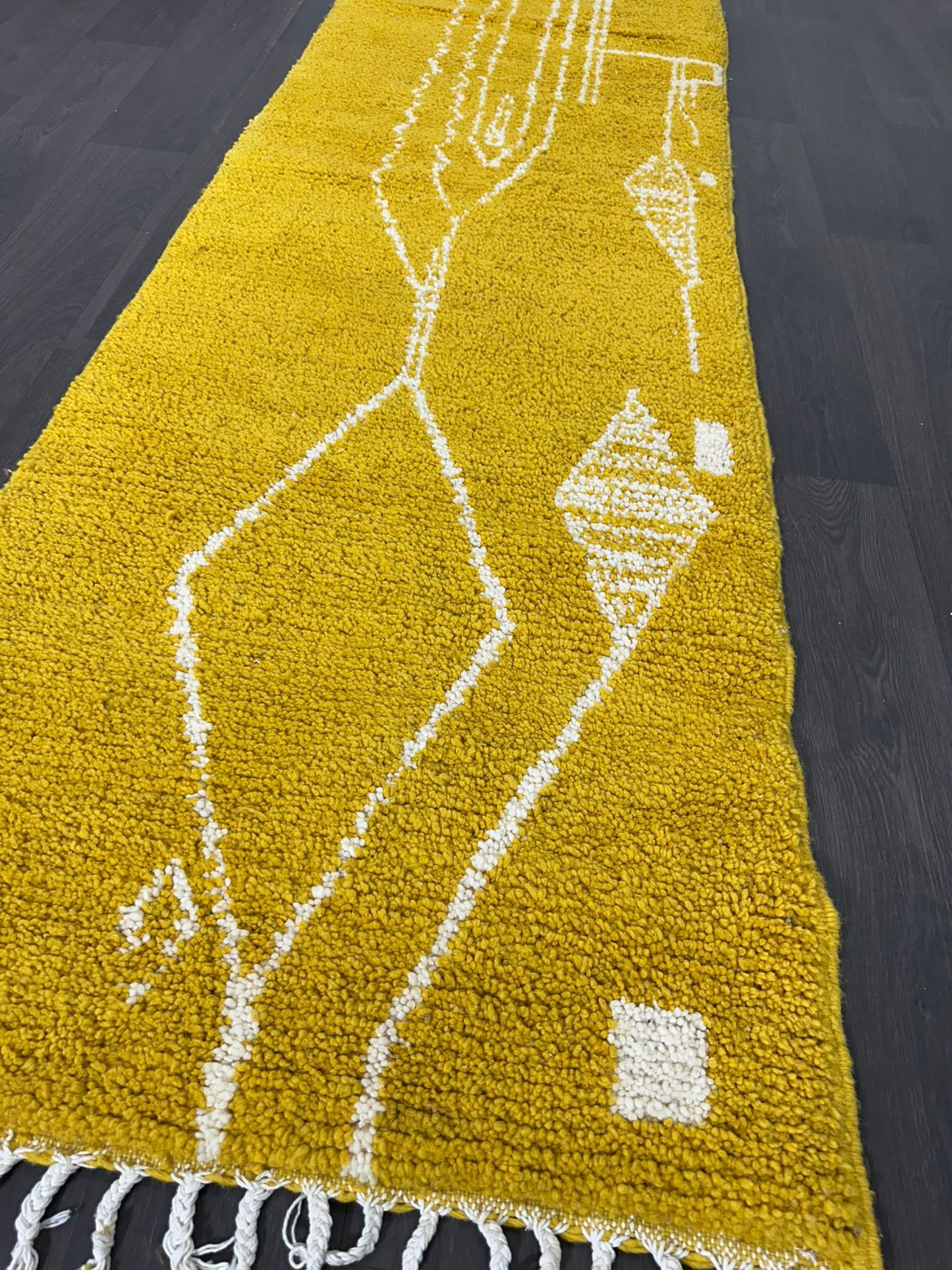 Yellow rug with white geometric patterns on a dark wooden floor