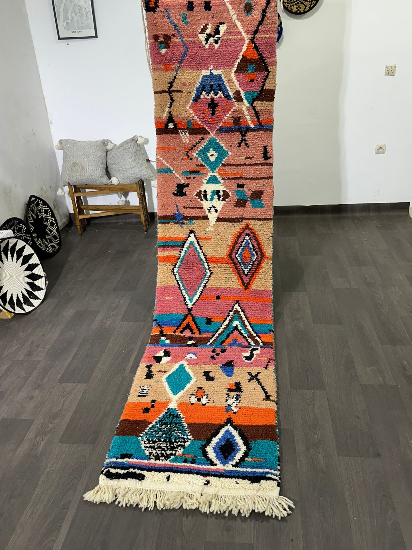 Colorful patterned rug on a wooden floor with a white wall background being held up