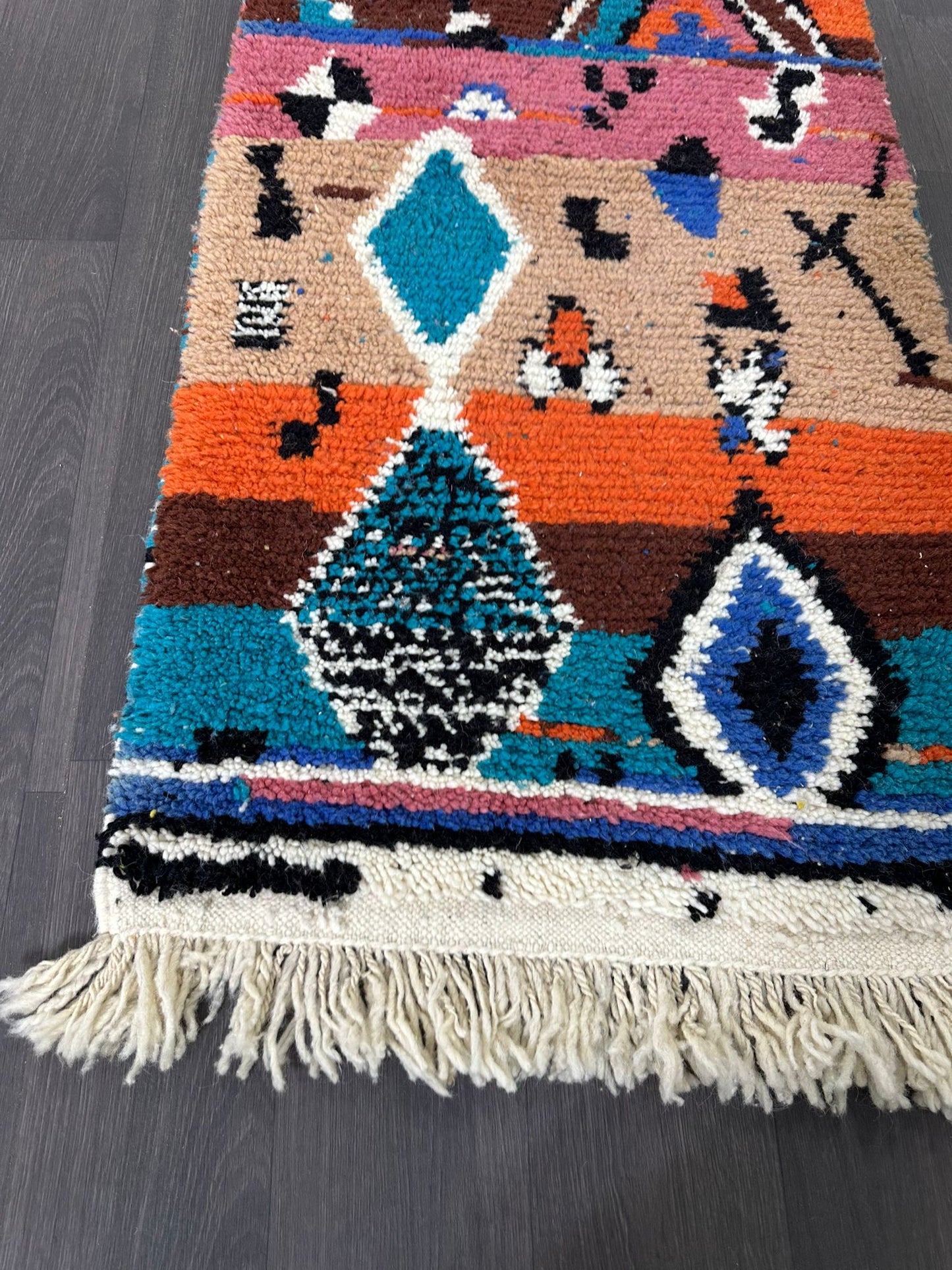 upclose photo of Colorful patterned rug with geometric designs on a dark wooden floor