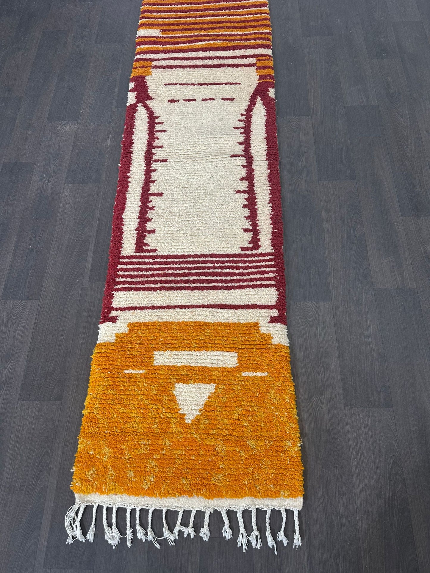 Colorful new Moroccan wool runner rug with geometric pattern on a dark wooden floor