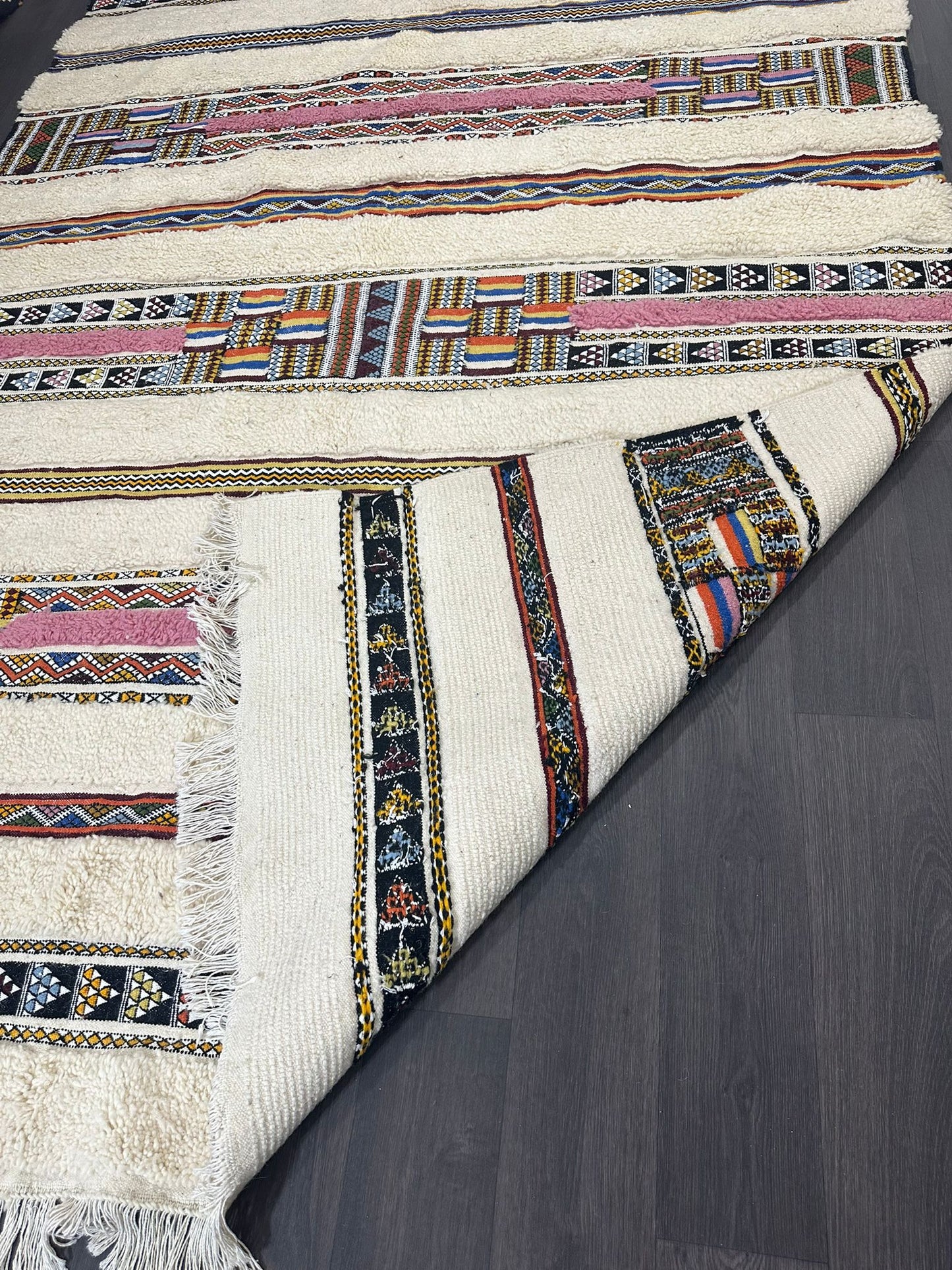 Close-up of a patterned rug with colorful stripes on a wooden floor.