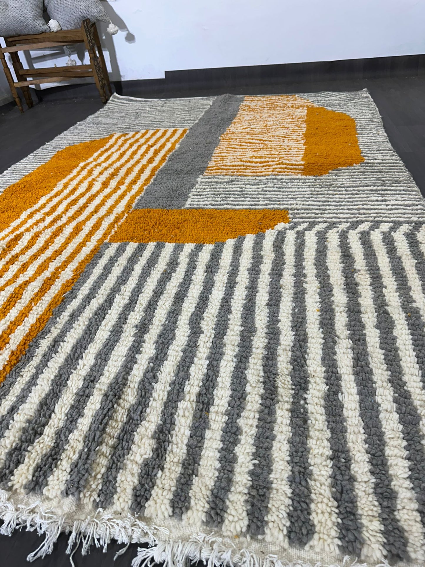 Geometric patterned rug with orange and gray stripes on a dark floor.