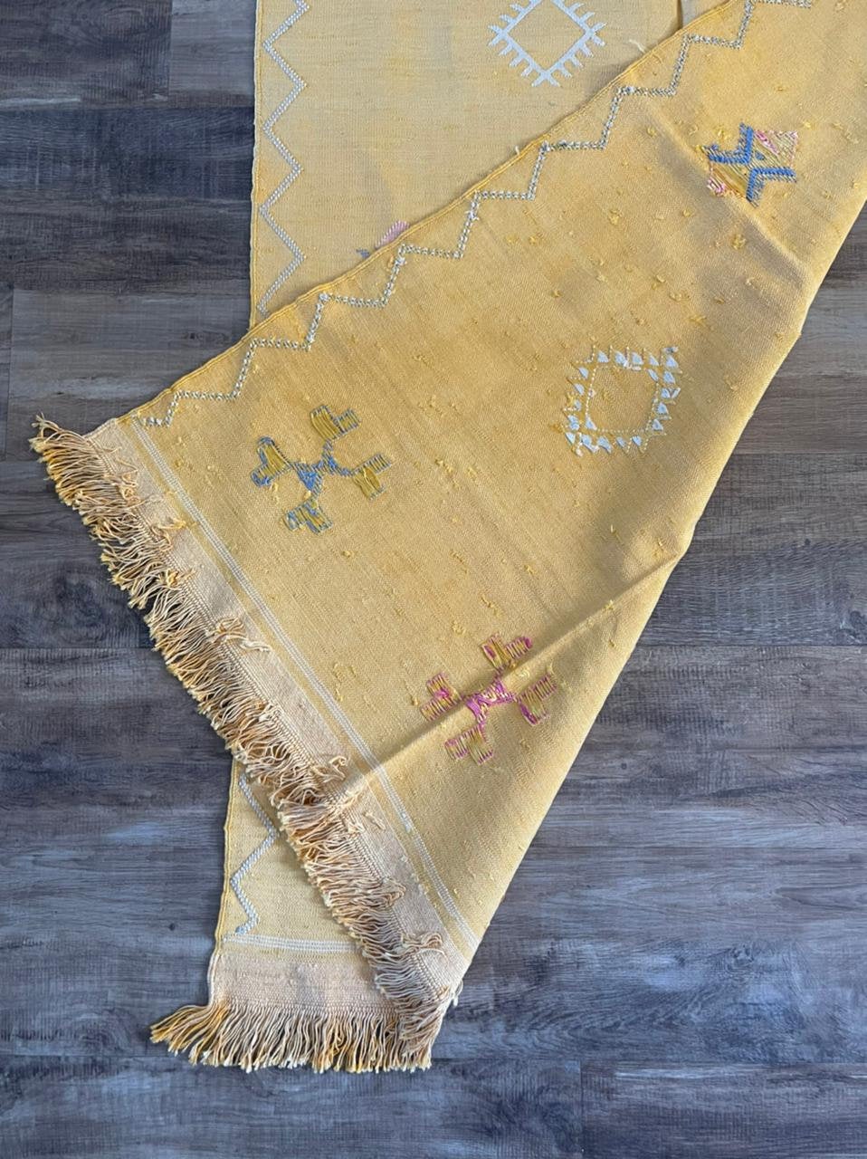 Yellow cactus silk rug with mutli coloured symbols woven into it