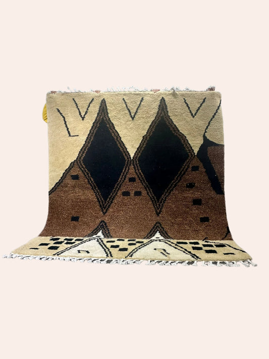 brown coloured rug with tribal lines and shapes being held up