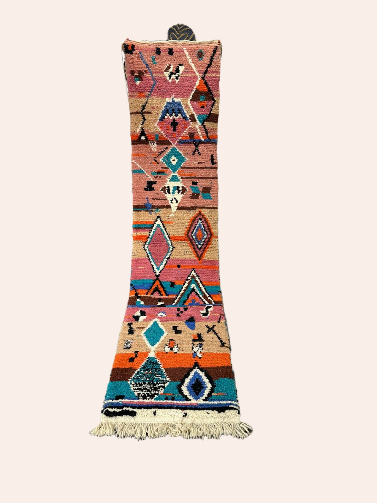 Colorful geometric-patterned rug on a wooden floor with decorative items in the background.