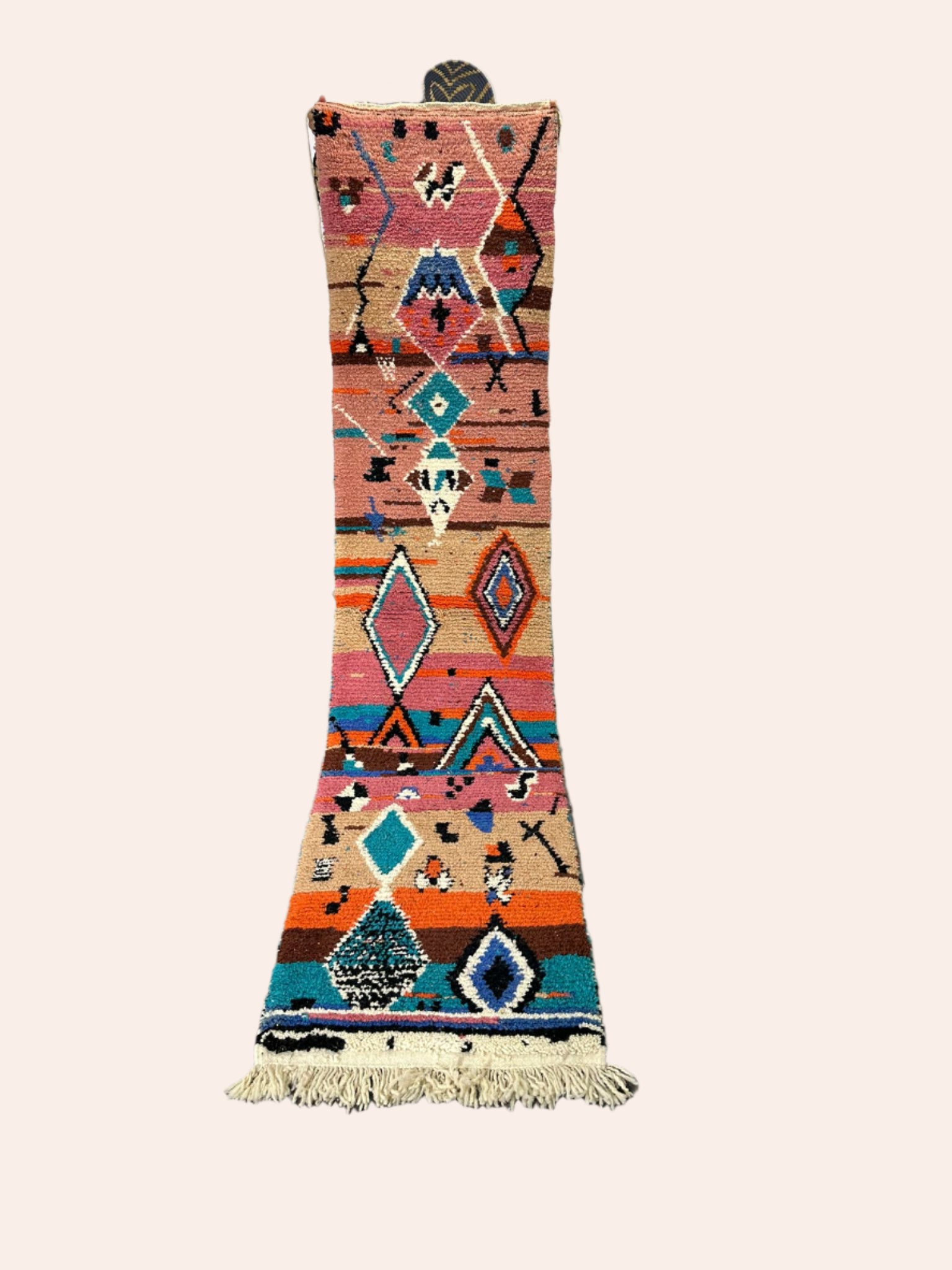 Colorful geometric-patterned rug on a wooden floor with decorative items in the background.