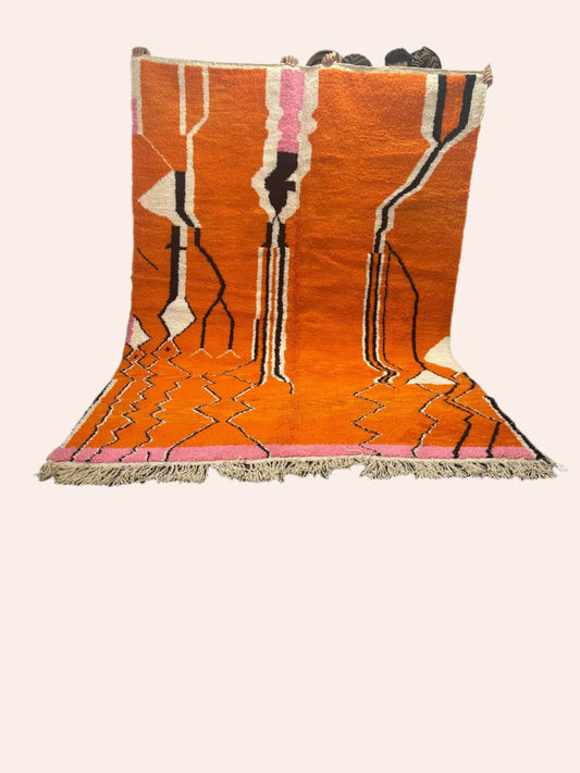 Hassanat is an orange rug with light pink, white and black lines in a tribal design
