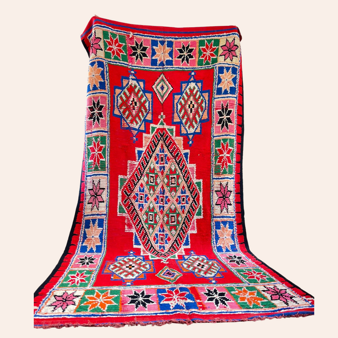 Red Moroccan vintage rug with tribal multi-coloured designs on a cream background