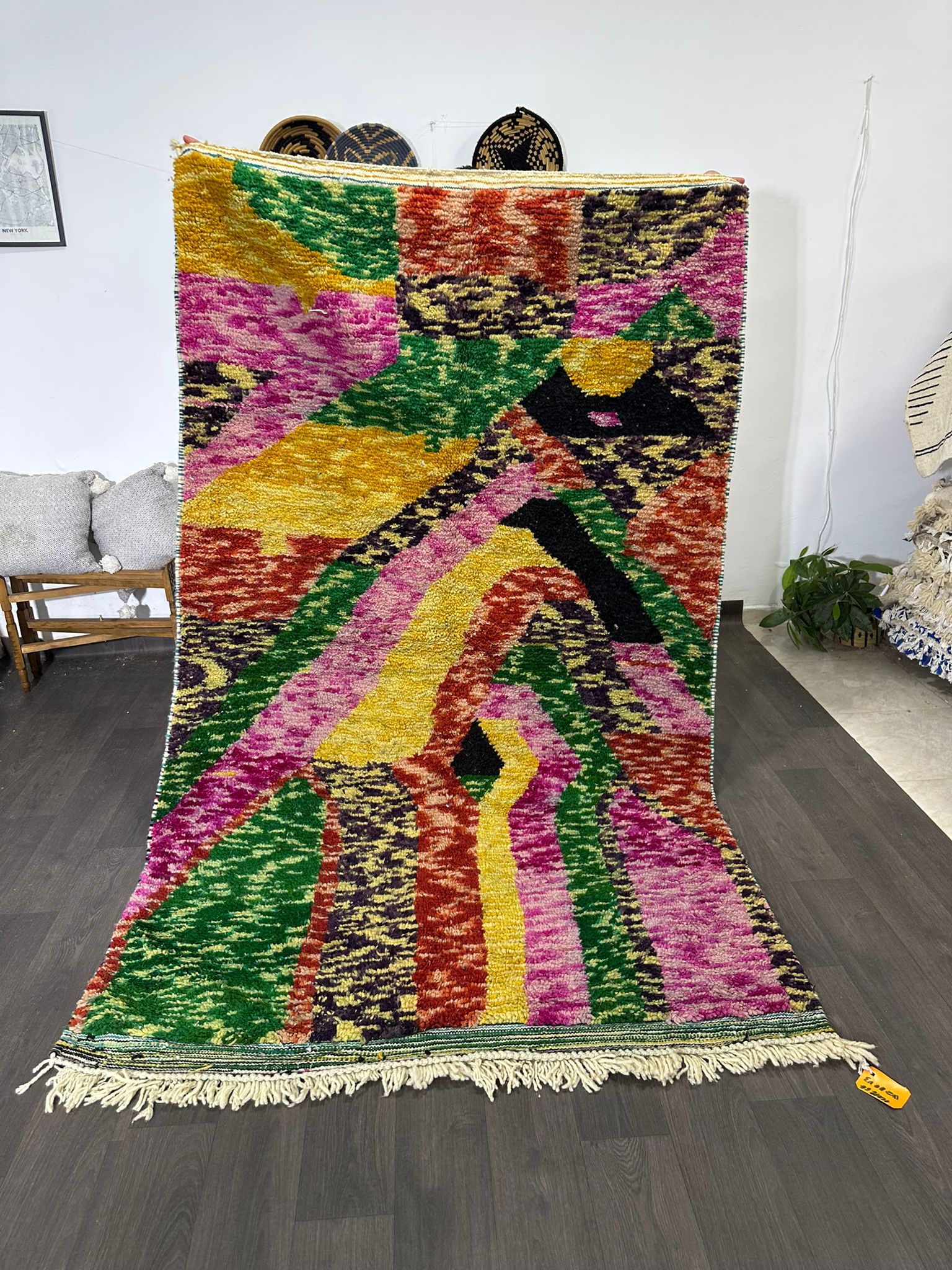 Colorful geometric-patterned rug on a wooden floor with a white wall background