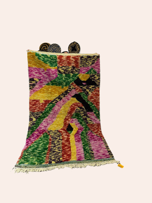 Colorful patterned rug on a wooden floor with a white wall background