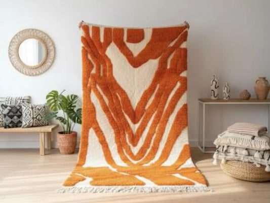 Orange and white patterned rug on a wooden floor with decorative items in the background.